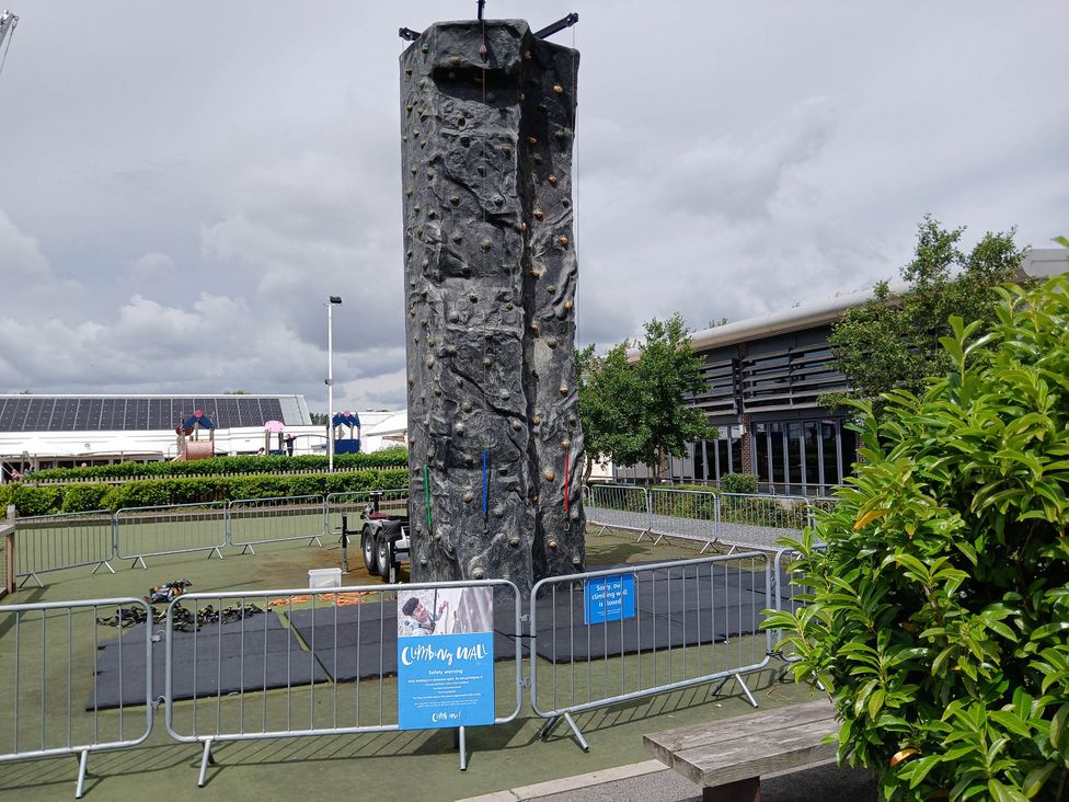 An outdoor climbing wall surrounded by mats and fences at a recreational area near Flookburgh