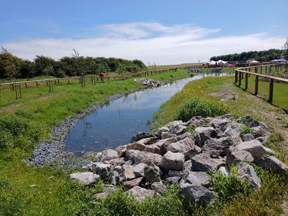 A stream with rocks and grass at a nature area near Flookburgh