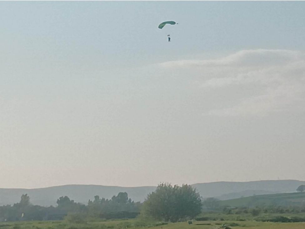 A paraglider flying in the sky with a landscape background near Flookburgh