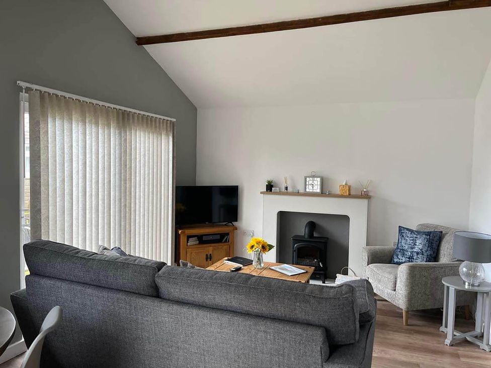 A living room with a sofa, TV, and a fireplace at The Old Barn in Bridlington