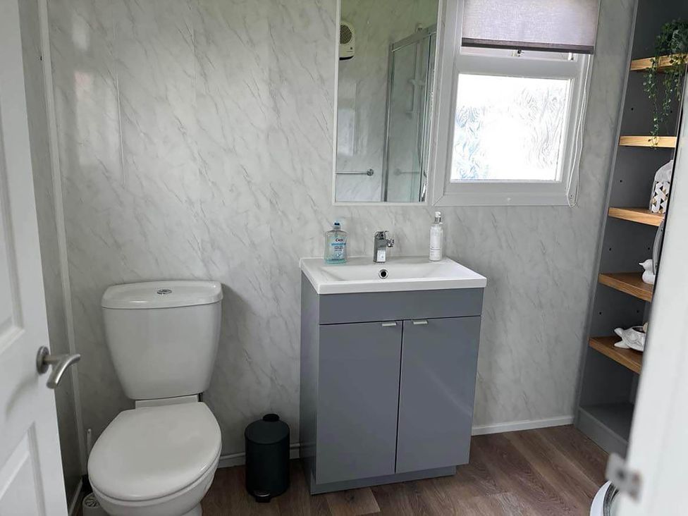 A bathroom with a sink, toilet, mirror, and shelving at undefined in Bridlington