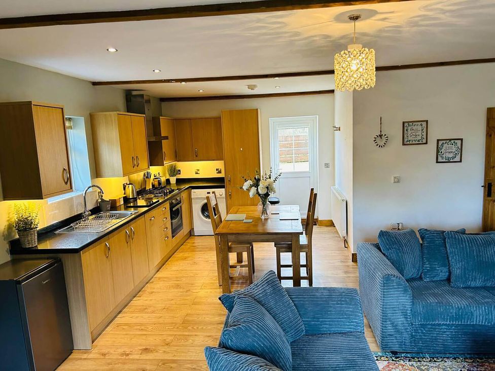 A kitchen with a dining table and sofa at The Old Barn in Nebo near Penygroes