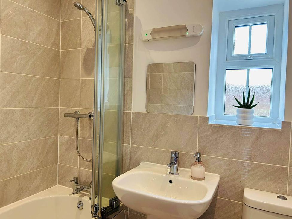 A bathroom with a shower, bathtub, sink, and window at Nebo near Penygroes