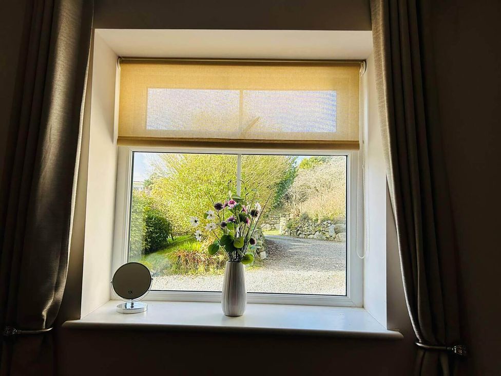 A window with a flower vase and a mirror at a property in Nebo near Penygroes