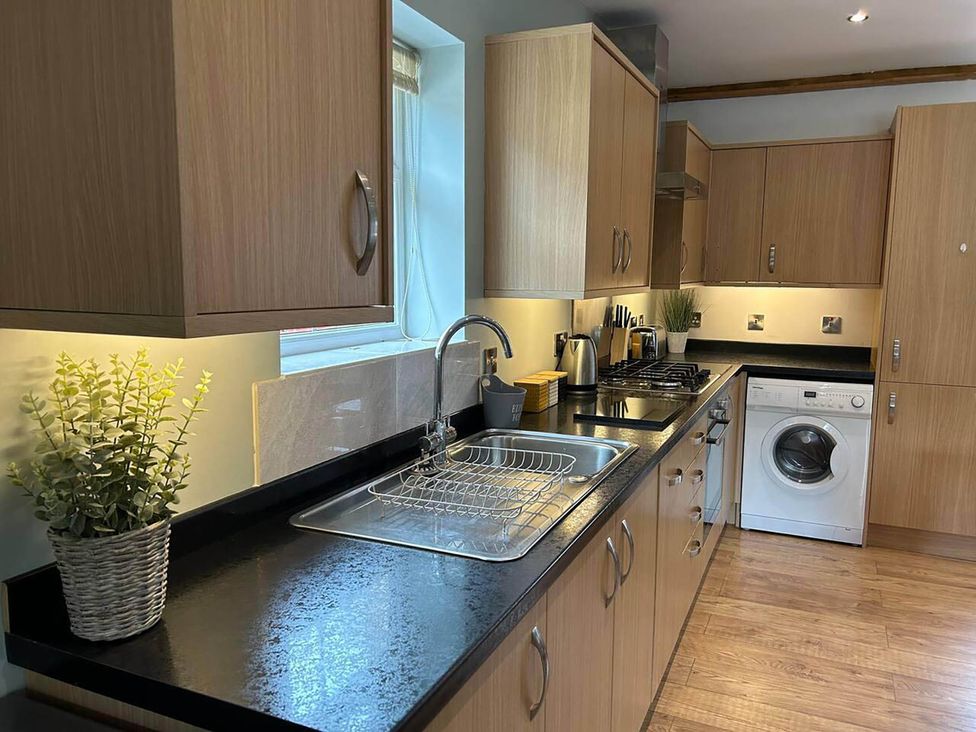 A kitchen with cabinets, sink, stove and washing machine at a property in Nebo near Penygroes