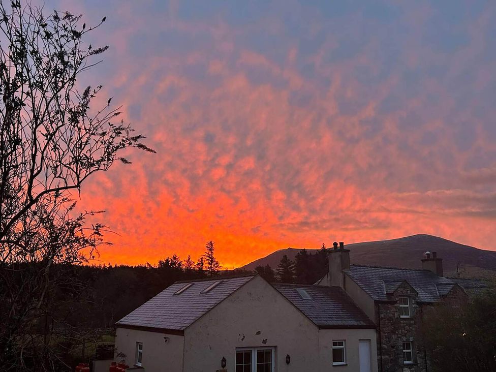 A sunset view with trees and houses in the foreground at Nebo near Penygroes