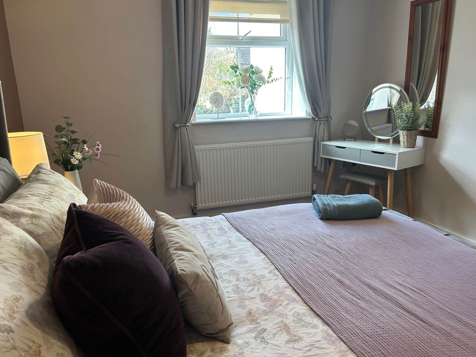 A bedroom with a bed, vanity, and window at the property in Nebo near Penygroes