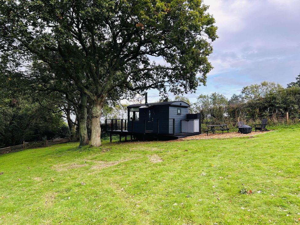 A hut with a deck and seating area surrounded by grass at a property in Newton Abbot