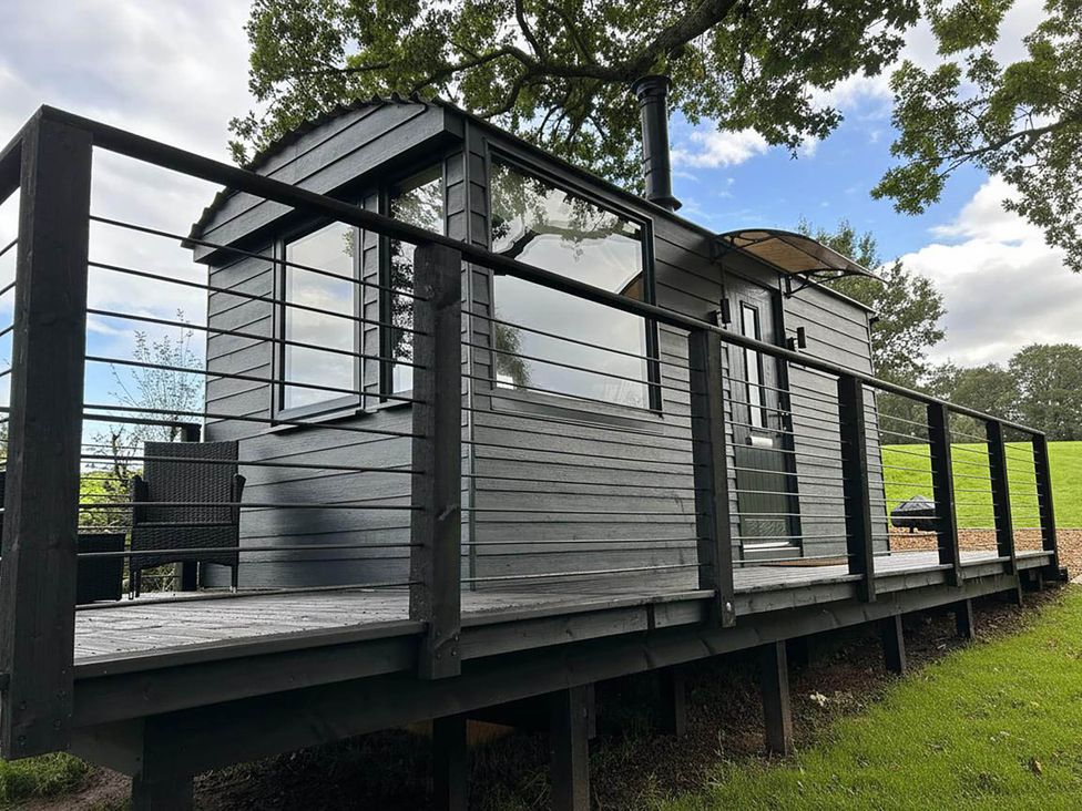 A cabin with a deck and railing at a property in Newton Abbot