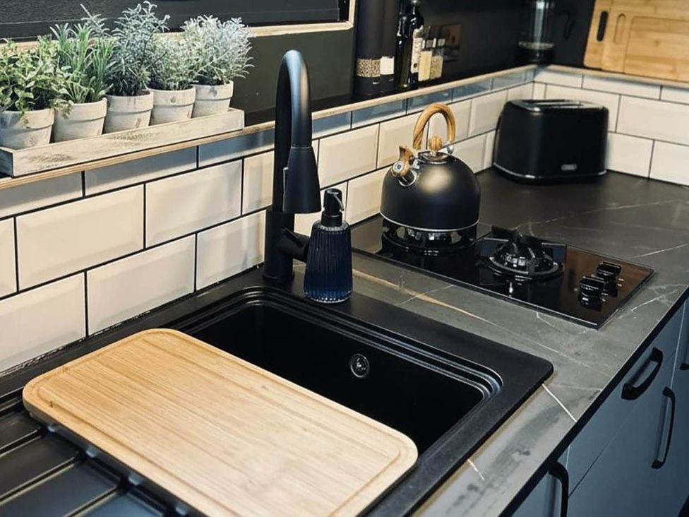 A kitchen with a sink, stove, kettle, and plants at The Old Barn in Newton Abbot