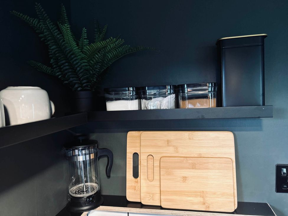A kitchen shelf with containers and a plant at 