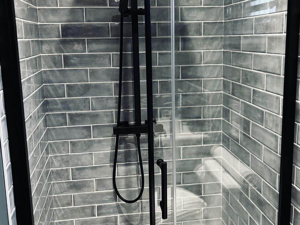 A shower with tiles and a glass door at The Old Barn in Newton Abbot
