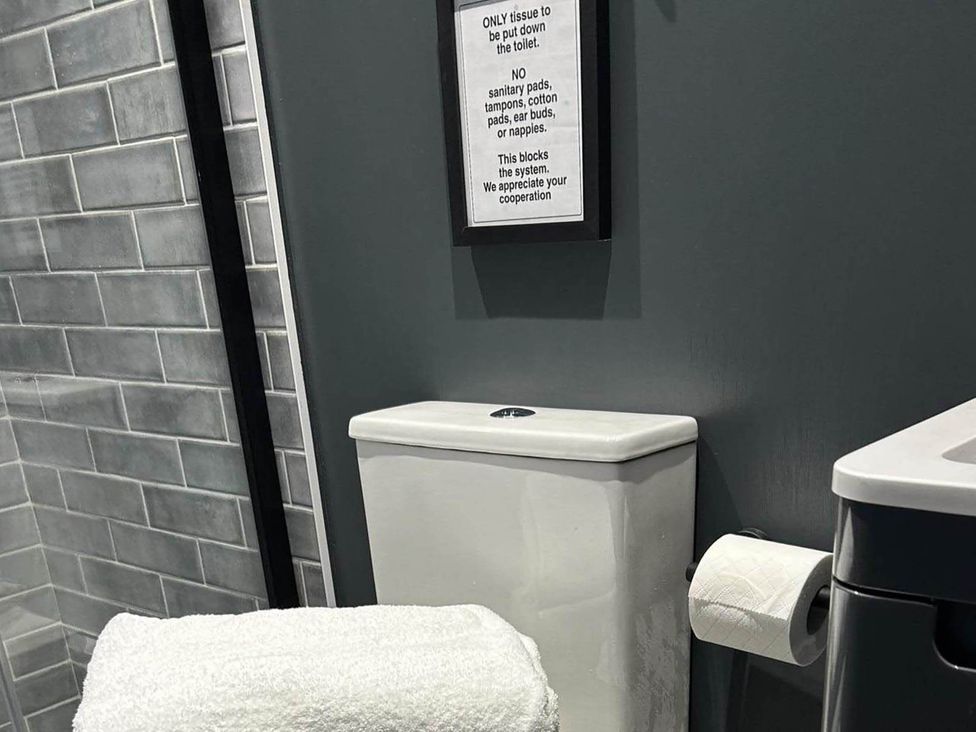 A bathroom with a toilet and a sign at The Old Barn in Newton Abbot