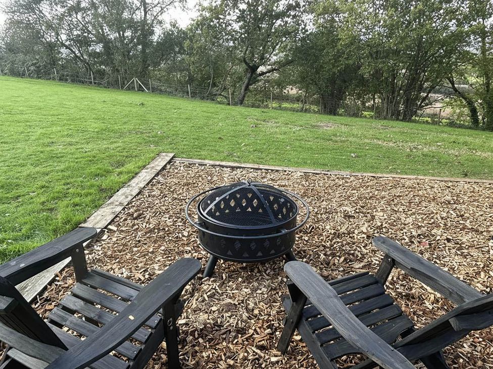 An outdoor area with a fire pit and wooden chairs in Newton Abbot