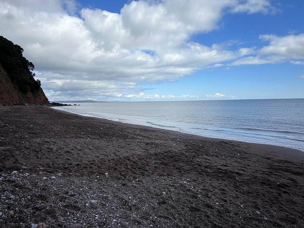 A beach with ocean and cliffs at The Old Barn in Newton Abbot