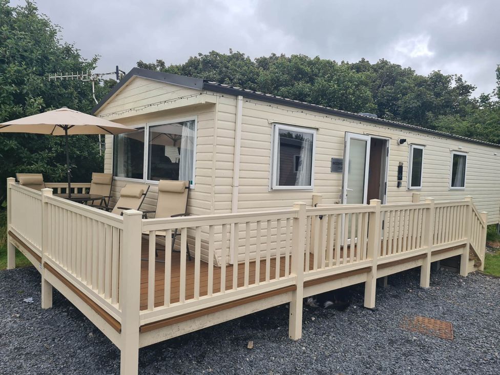 A cabin with a deck and outdoor furniture at a holiday park