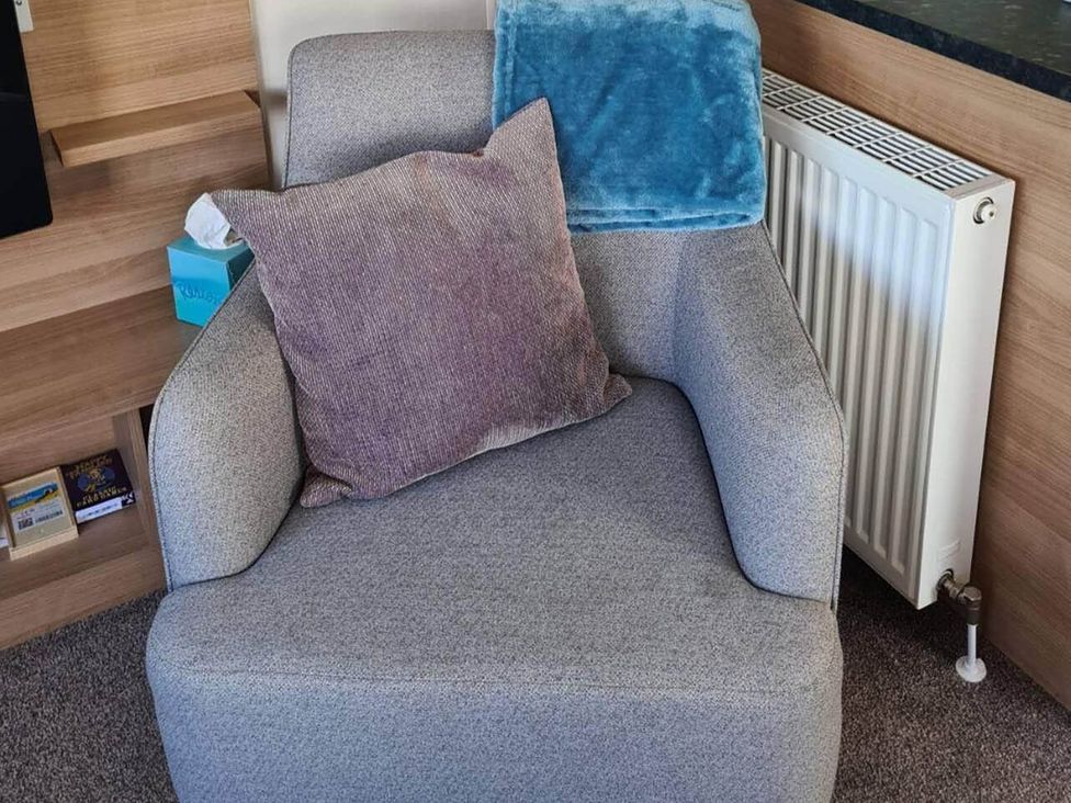 An armchair with cushions and a throw blanket at 