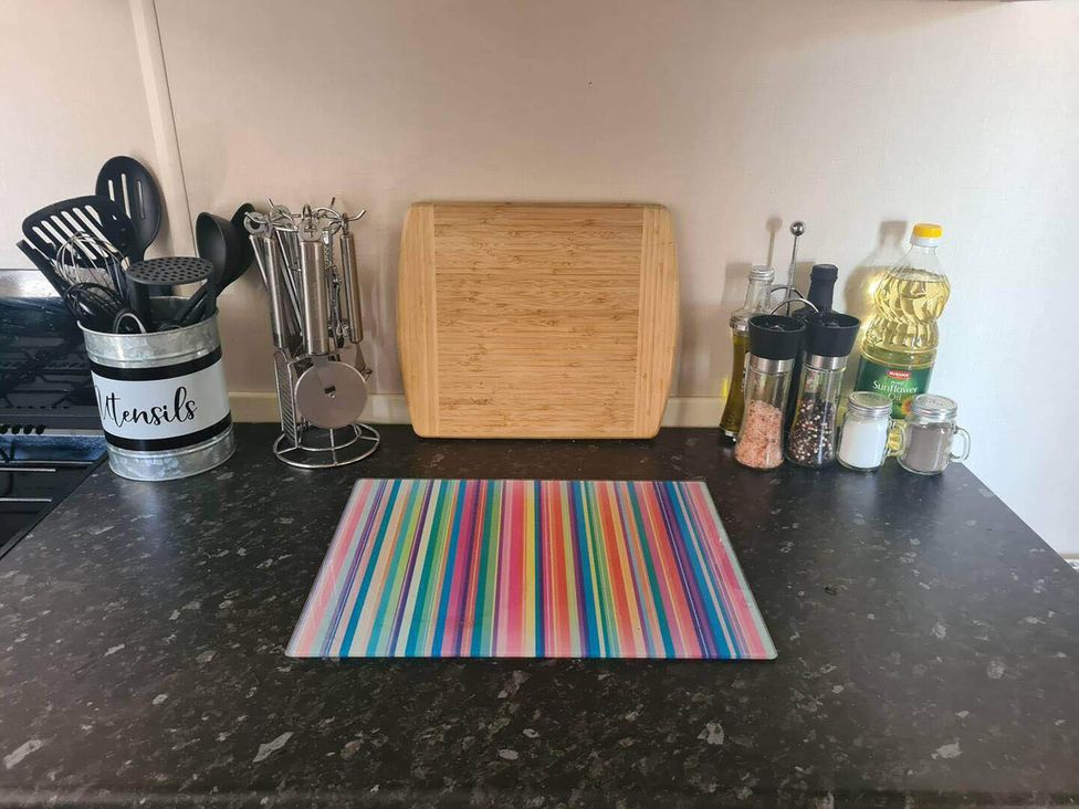 A kitchen countertop with utensils and a cutting board at 