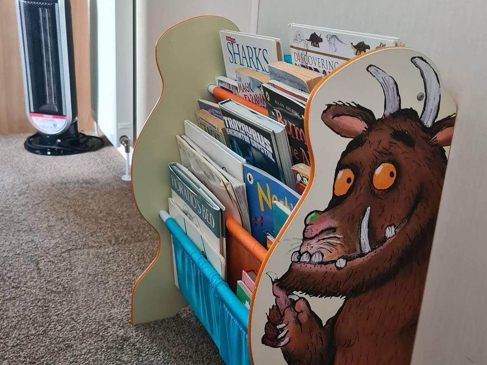 A bookshelf with children's books and an illustrated character at a reading nook