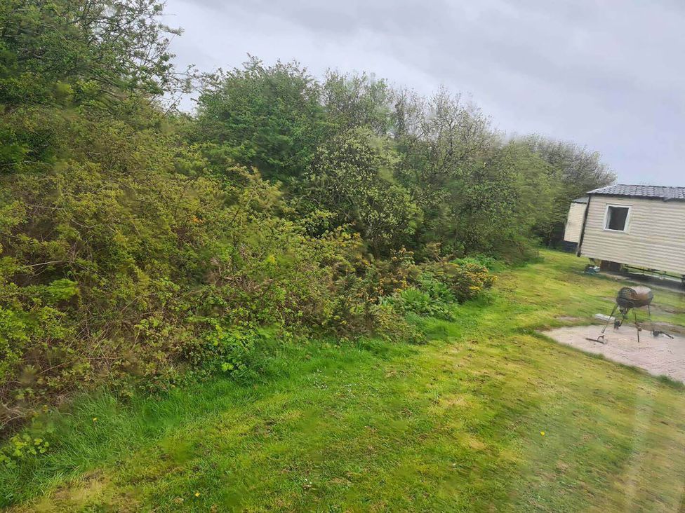 An outdoor area with bushes and a mobile home at a location