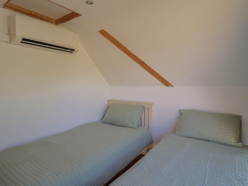A bedroom with two single beds and an air conditioning unit at The Linhay Cotleigh Nr. Honiton