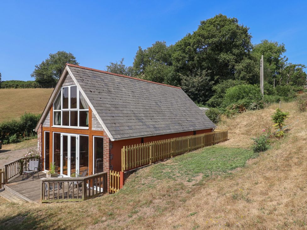 A house with a deck and fence in a grassy area at The Linhay Cotleigh Nr. Honiton