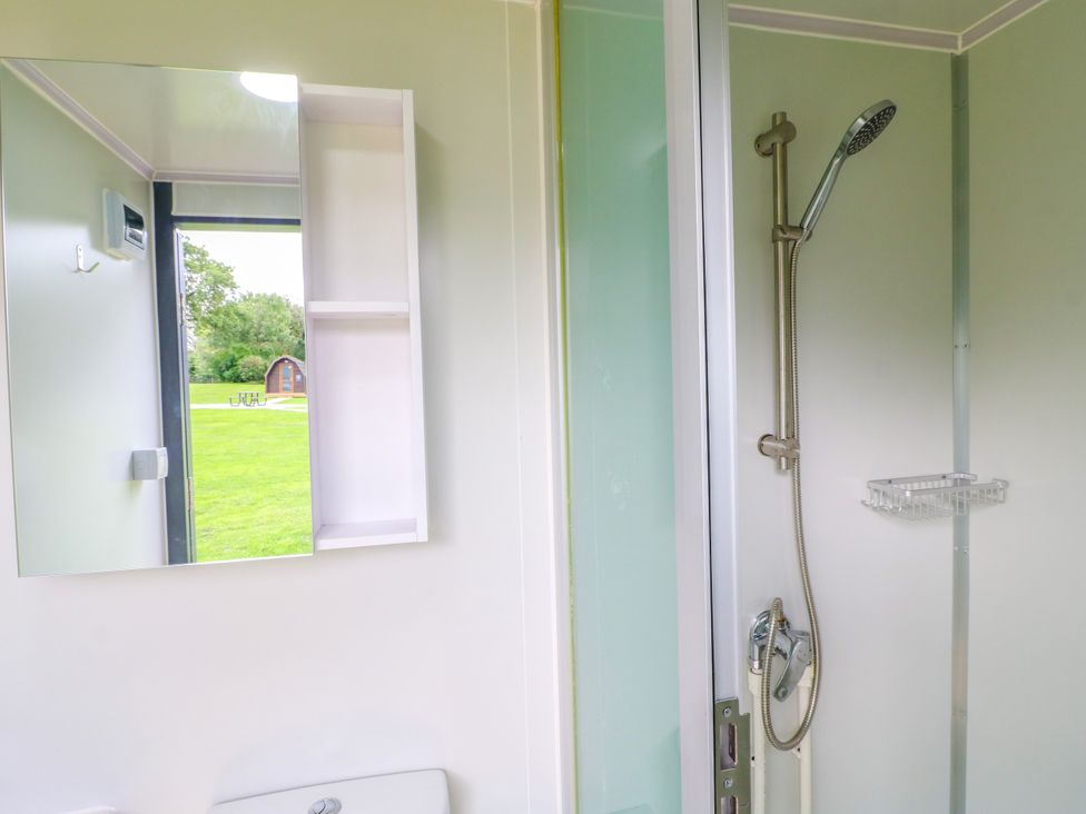 A bathroom with a shower and a mirror at Goldfinch Pod Swannington near Coalville