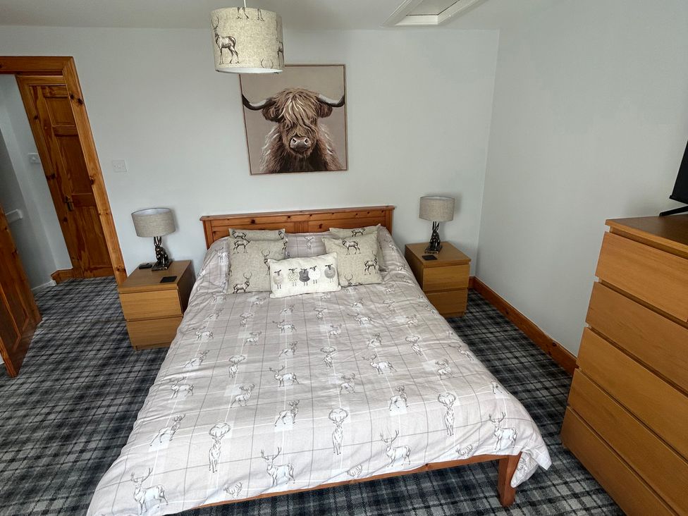 A bedroom with a bed, bedside tables, and a dresser at 1 Station Cottages 