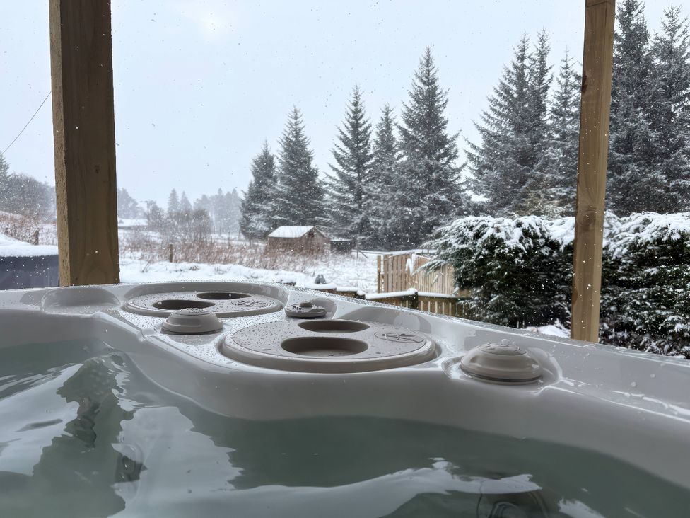 A hot tub with water and snow in an outdoor area at 1 Station Cottages