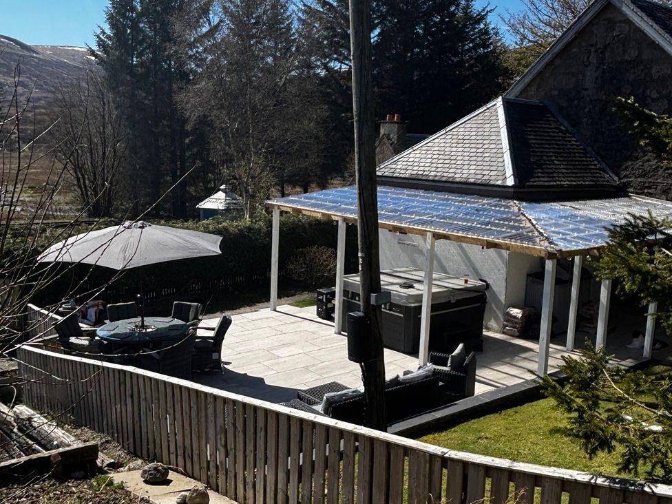 An outdoor area with a patio table and chairs near a hot tub at 1 Station Cottages