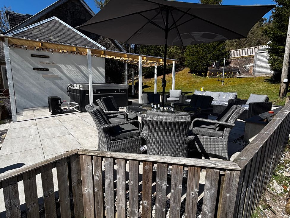 An outdoor patio with seating and a hot tub at 1 Station Cottages