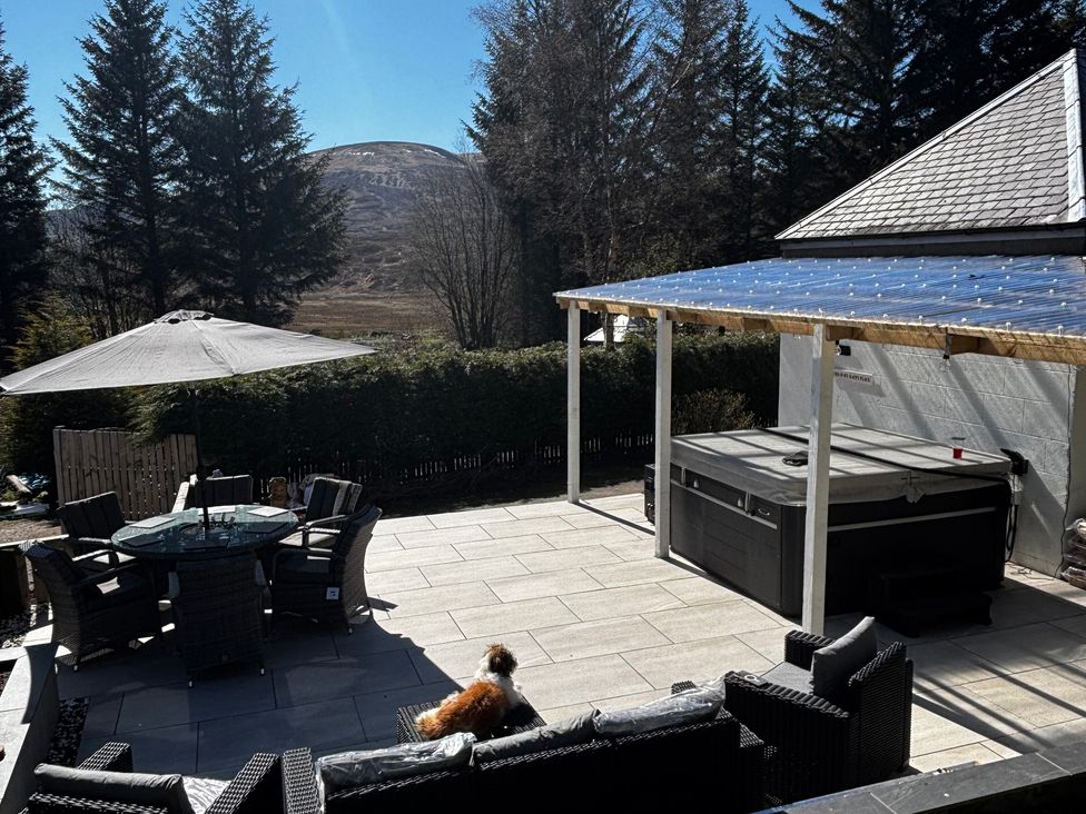 A patio area with a table, chairs, and hot tub at 1 Station Cottages