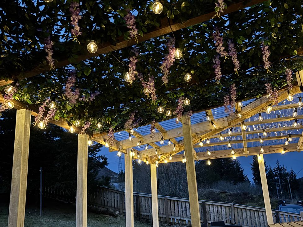 An outdoor structure with lights and flowers at 1 Station Cottages