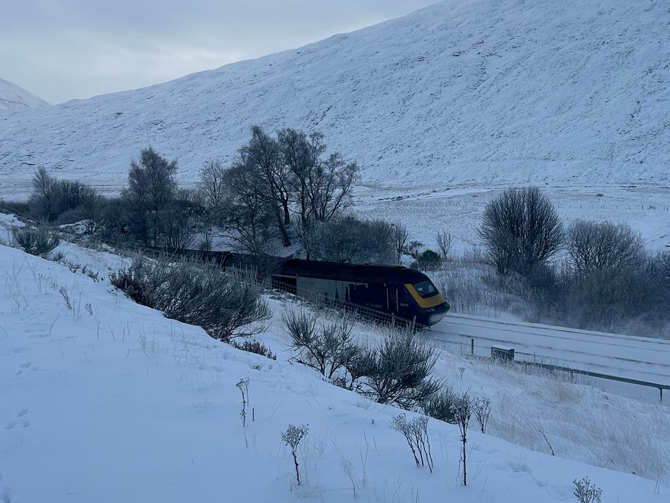 A train traveling through snow-covered mountains at 1 Station Cottages 