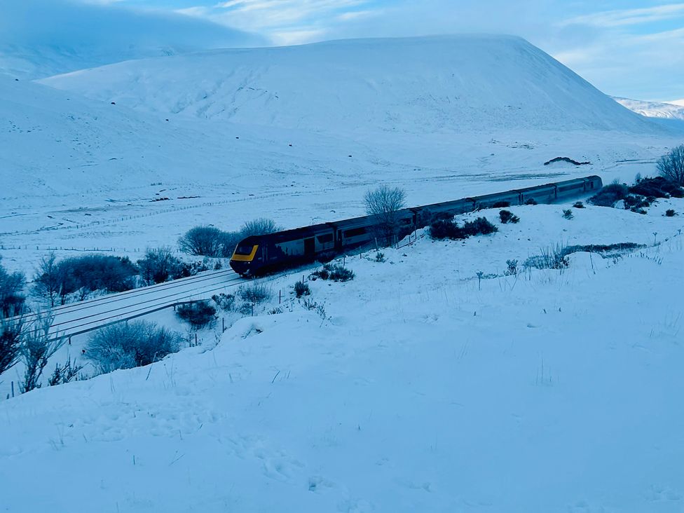 A train on railway tracks in snow covered landscape at 1 Station Cottages