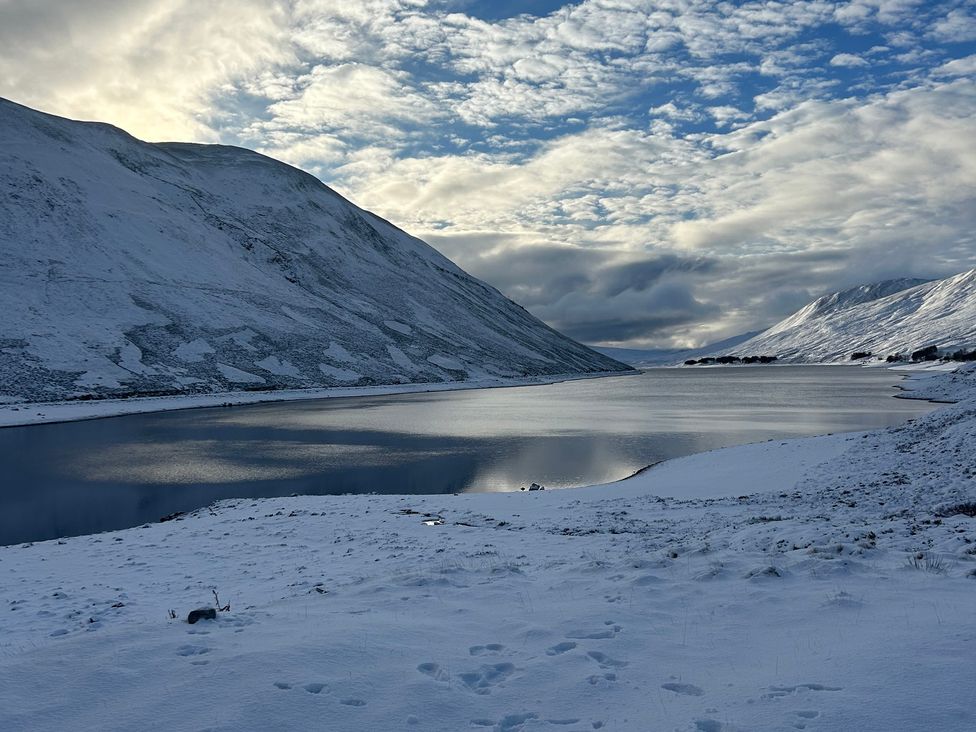 A snowy landscape with a lake and mountains at 1 Station Cottages