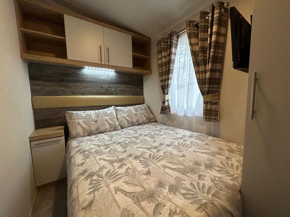 A bedroom with a bed and shelves at Rockley Park in Poole