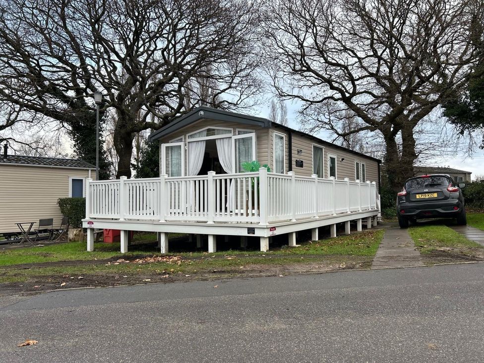 A mobile home with a deck and a car at Rockley Park in Poole
