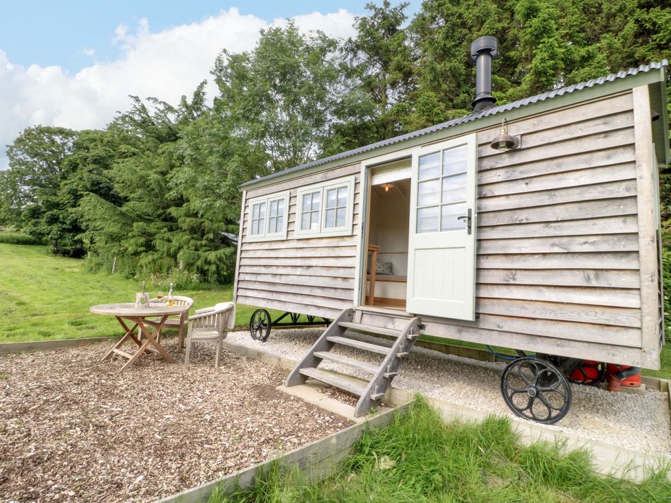 A shepherd hut with a table and chairs outside at Pike House Farm Shepherds Hut 2 Ashbourne