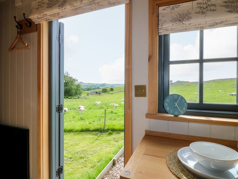 A kitchen with a window and a view of a rural landscape at Pike House Farm Shepherds Hut 2 Thorpe near Ashbourne