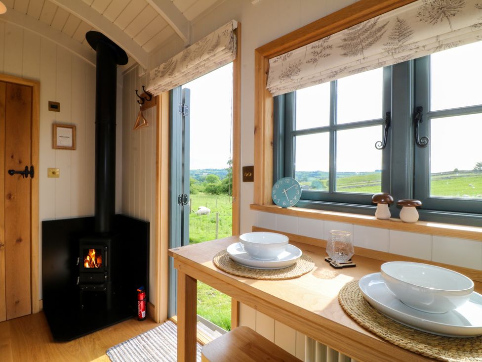 A kitchen with a table and wood stove at Pike House Farm Shepherds Hut 2 Thorpe near Ashbourne