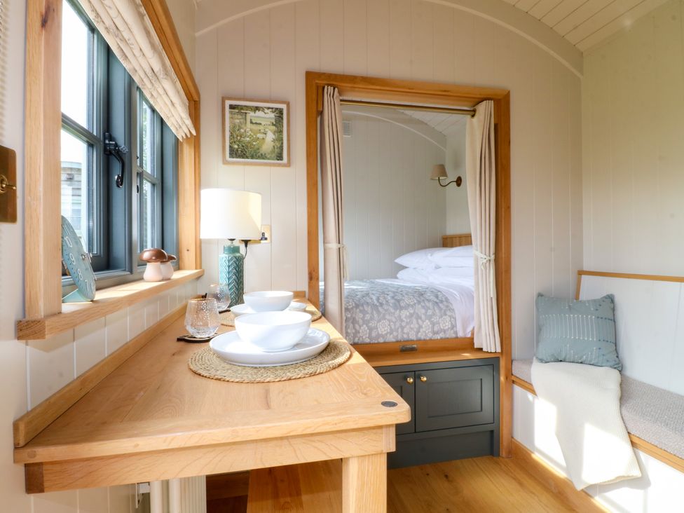 A bedroom with a bed and table at Pike House Farm Shepherds Hut 2 Thorpe near Ashbourne