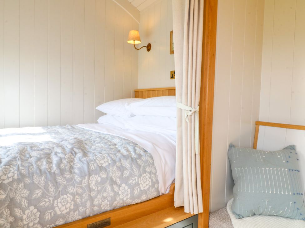 A bedroom featuring a bed and bedside lamp at Pike House Farm Shepherds Hut 2 Thorpe near Ashbourne