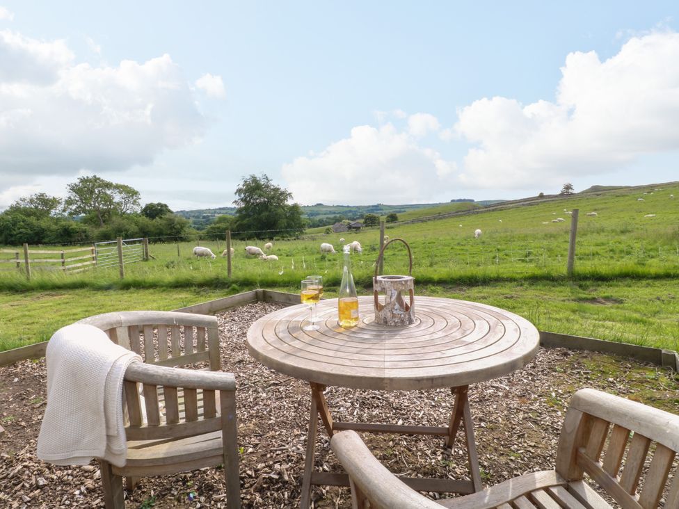 A seating area with a table and chairs overlooking a field at Pike House Farm Shepherds Hut 2 Thorpe near Ashbourne