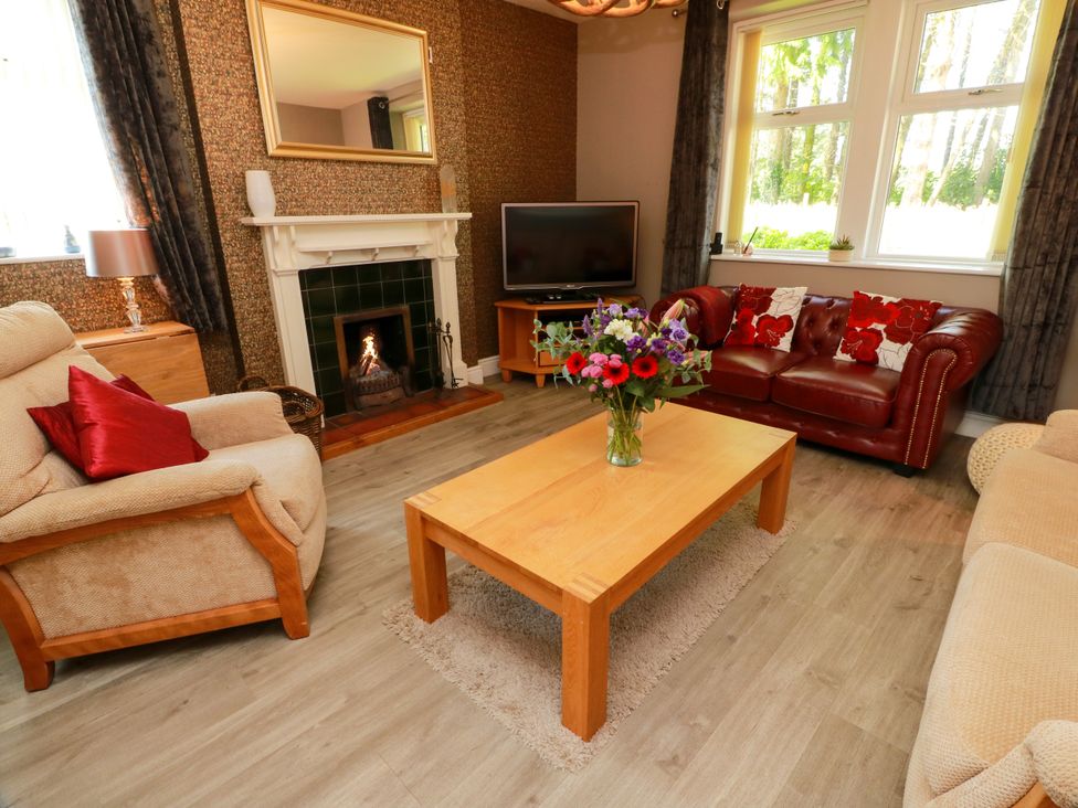 A living room with a coffee table and a television at Waterside Lodge in Annan