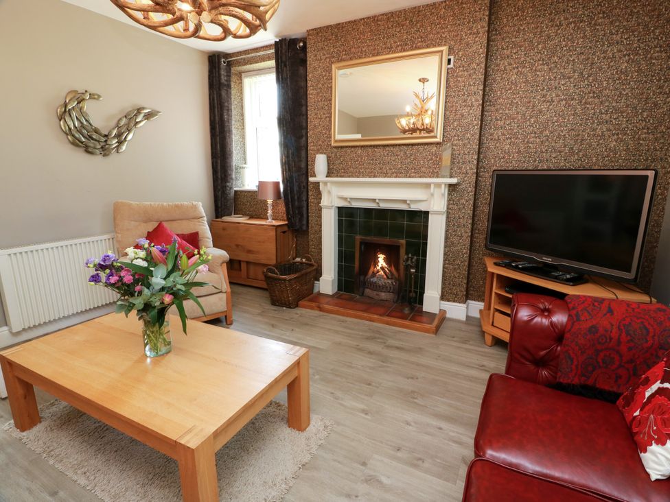 A living room with a sofa, coffee table, and fireplace at Waterside Lodge in Annan