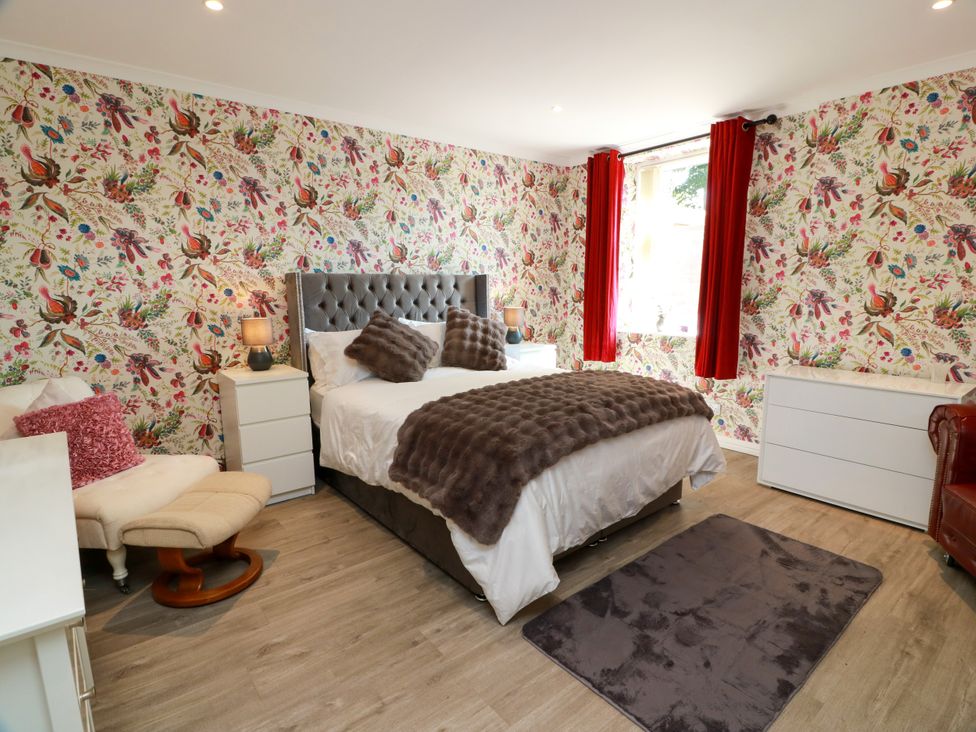 A bedroom with a bed and a chair at Waterside Lodge Annan