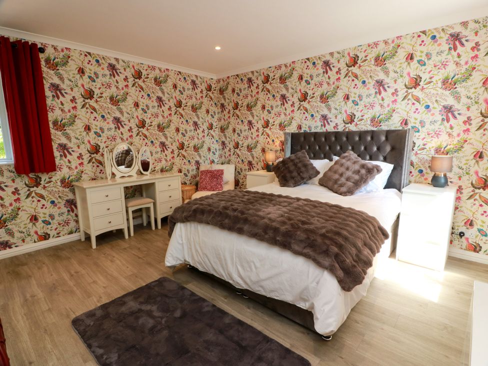 A bedroom with a bed and dressing table at Waterside Lodge in Annan