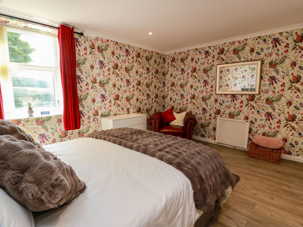 A bedroom with a bed, chair, and window at Waterside Lodge in Annan