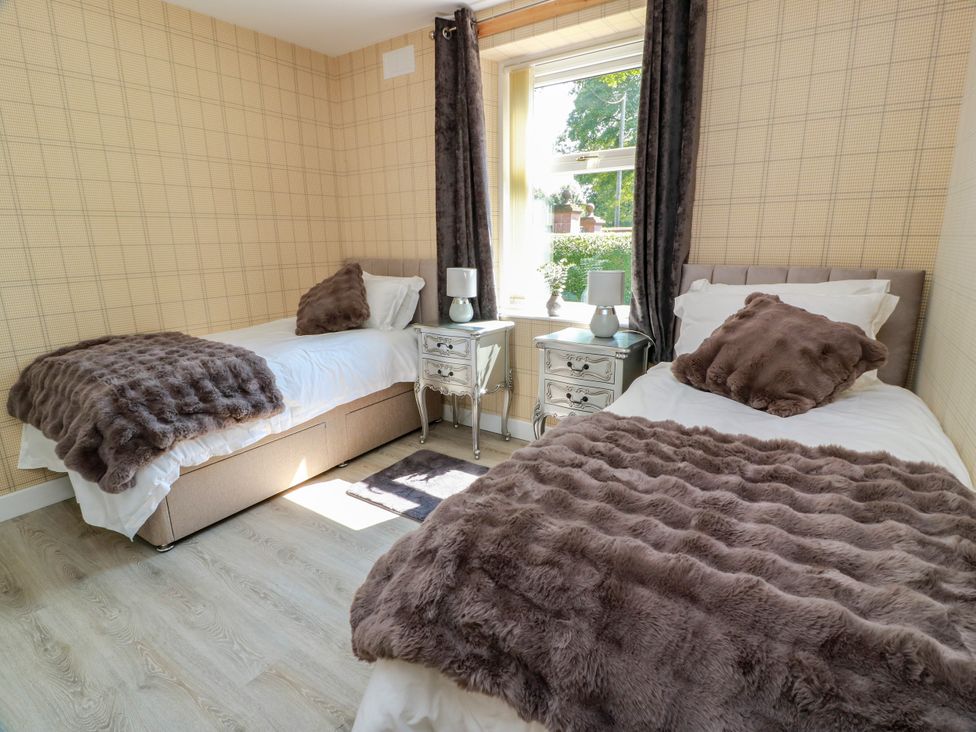 A bedroom with twin beds and a nightstand at Waterside Lodge in Annan